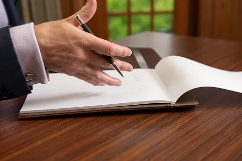 Handing holding a pen with a book.